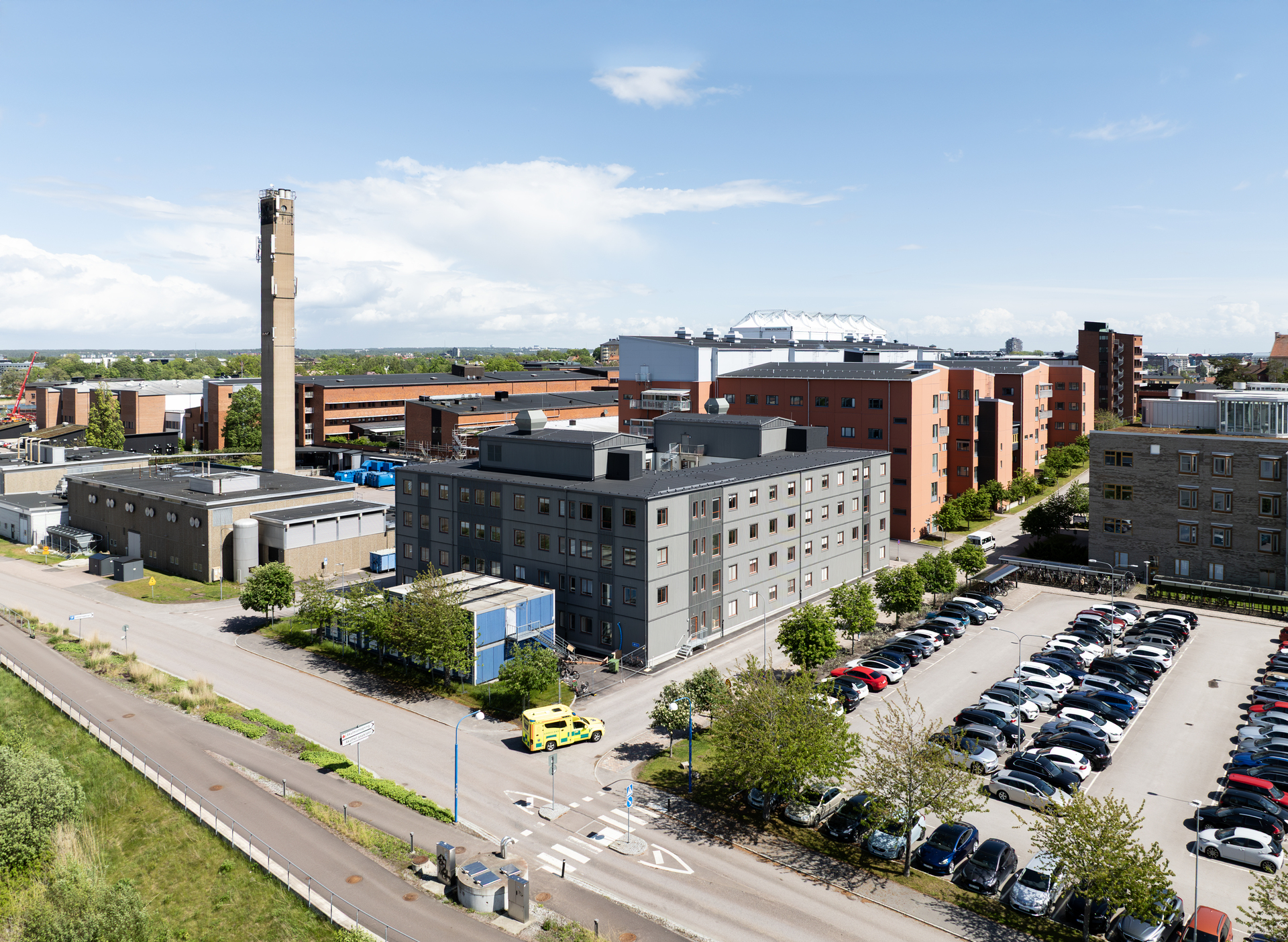 Flygfoto över Centralsjukhuset i Karlstad med kontorsmoduler från Expandia i förgrunden. De grå modulbyggnaderna är placerade intill sjukhusets övriga byggnader och parkeringar och visar hur Expandias flexibla kontorsmoduler är integrerade i sjukhusområdet och bidrar med tillfälliga och permanenta arbetsmiljöer.