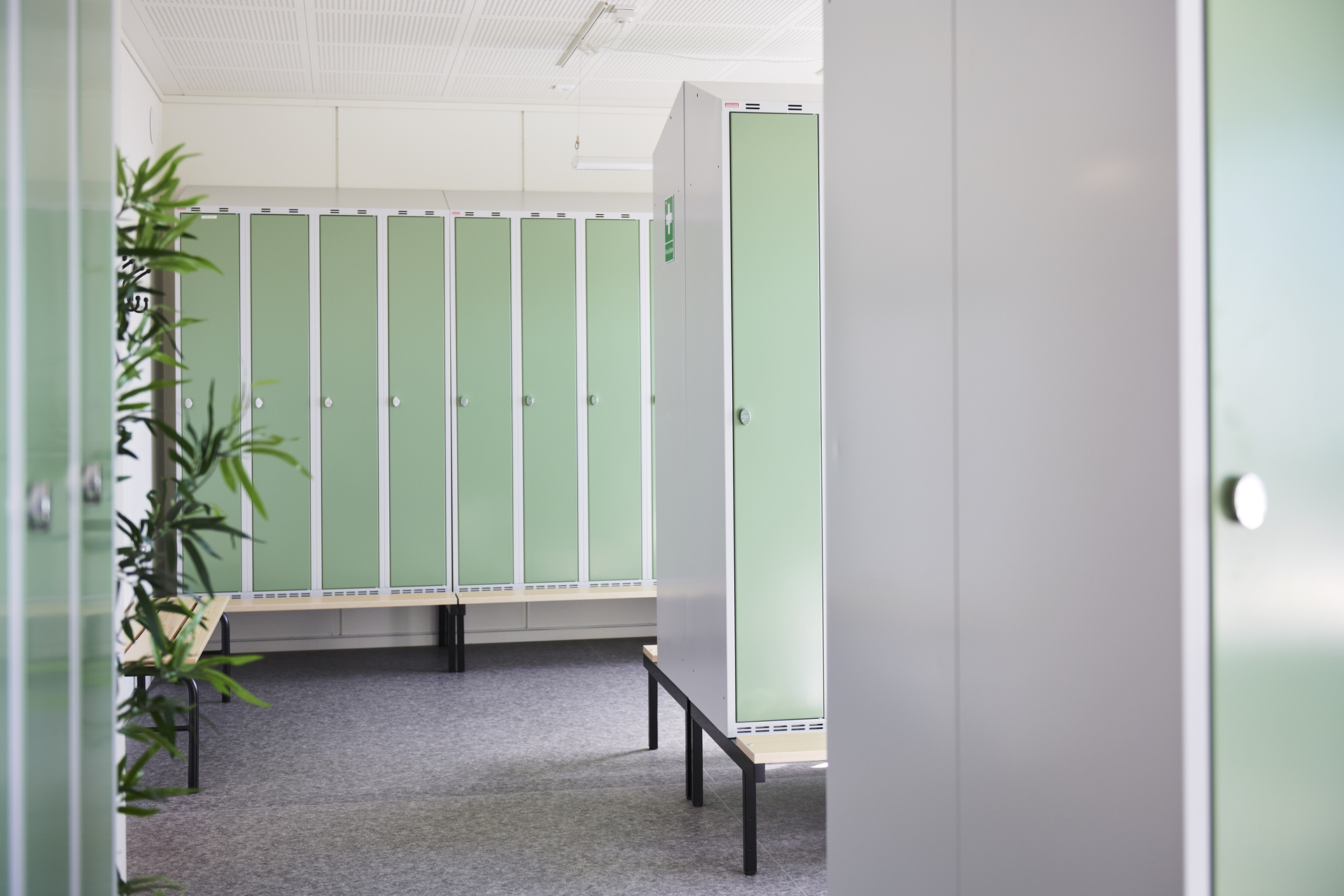 Omklädningsrum i kontorsmoduler från Expandia med gröna förvaringsskåp i rader och sittbänkar. Rummet är ljust och funktionellt, med plats för ombyte och förvaring. Bilden är tagen i kontorsmoduler vid Alviks trafik i Luleå.