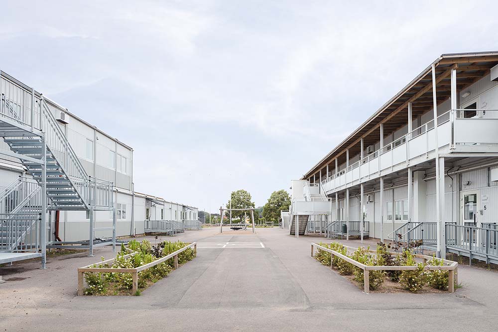 Gårdsyta mellan skolmodullösning från Expandia vid Rebbelberga skola i Ängelholm, med två våningsplan, utvändiga trappor, entréer och planteringar.