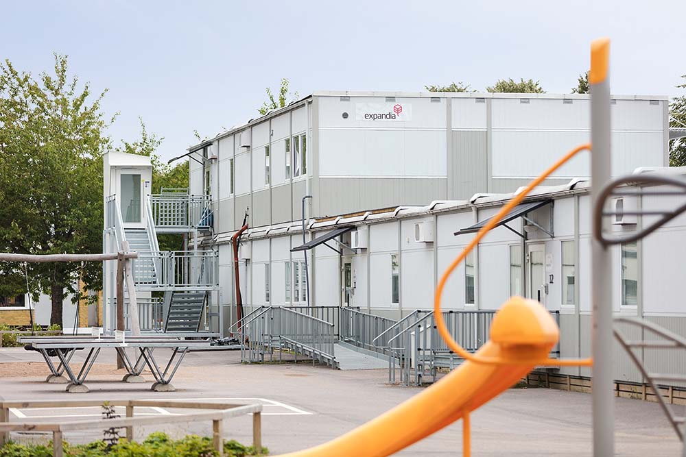 Skolmodullösning från Expandia vid Rebbelberga skola i Ängelholm, med två våningsplan, utvändiga trappor, ramper och skolgård med lekutrustning i förgrunden.