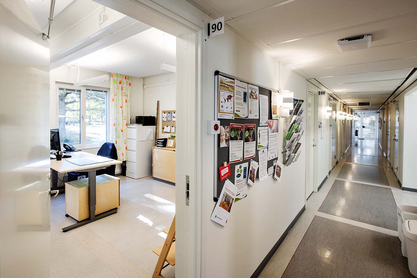 Korridor och behandlingsrum i vårdmottagning uppförd med moduler från Expandia, med informationsanslag på vägg och ljusa arbetsytor.