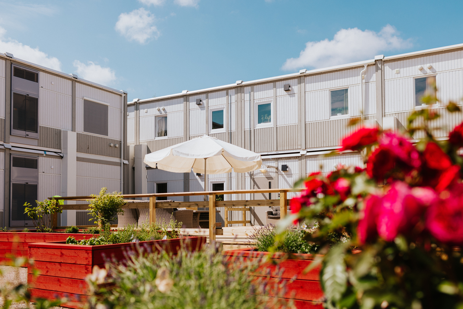 fin innergård med blommor och bostadsmoduler i bakgrunden