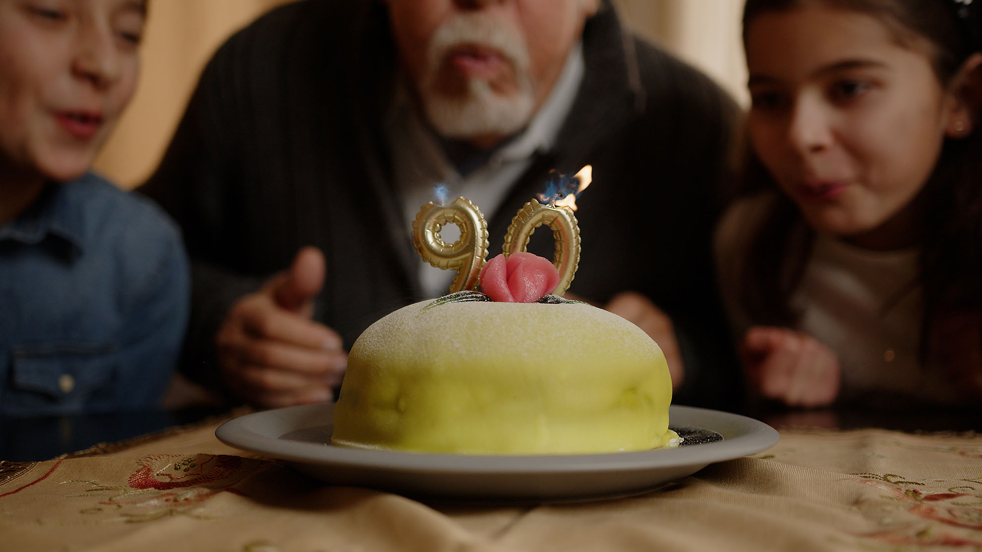 äldre man blåser ut ljus på tårta. födelsedagsfirande i moduler